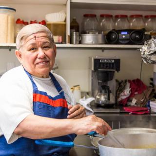 A chef in a kitchen stirring a pot.