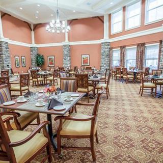 An elegant and spacious dining room with neatly arranged tables and chairs, adorned with decorative chandeliers.
