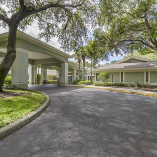 A scenic view of a building entrance surrounded by trees and lush landscaping.