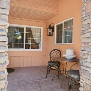 Cozy patio area with stone columns, a small table and chairs, and decorative windows.