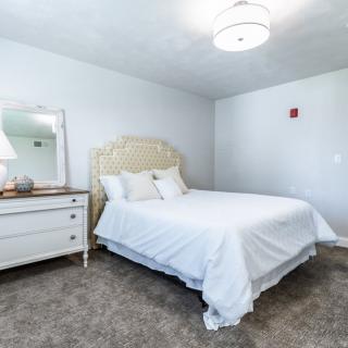 A bright and minimalistic bedroom with a cozy bed, dresser, and mirror.