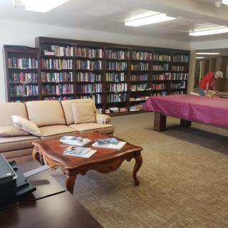 A cozy library lounge with bookshelves, a sofa, and a pool table.