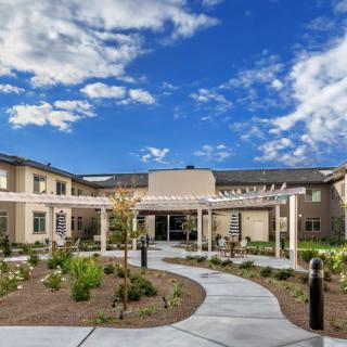 A modern building with a landscaped garden and clear blue sky.