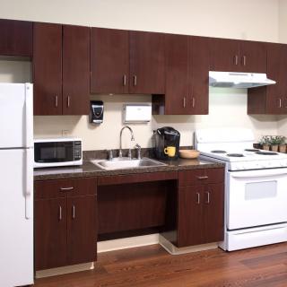 A modern kitchen with dark wood cabinets, a white stove, refrigerator, microwave, and a sink.