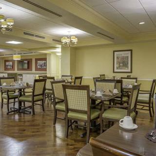 An empty dining room with neatly arranged tables and chairs, featuring cozy lighting and wooden flooring.