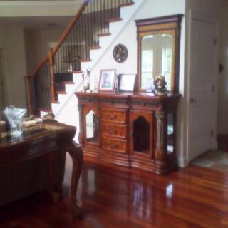 A cozy living room with a wooden staircase and polished hardwood floors.