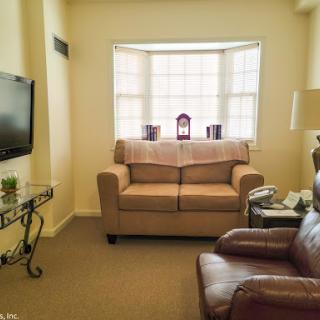 A cozy living room setup featuring a beige sofa, an armchair, and a television.