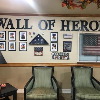 A wall decorated to honor heroes, featuring photographs, American flags, and seating.