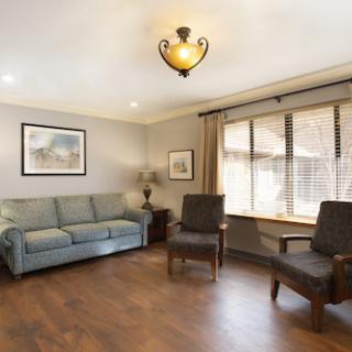 A cozy living room featuring a sofa, two chairs, and natural light streaming through the window.