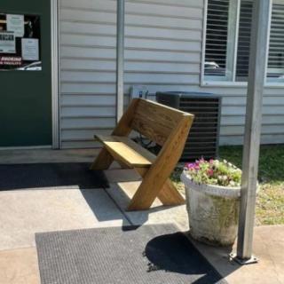 A wooden bench near the entrance of a building, with a plant pot beside it.