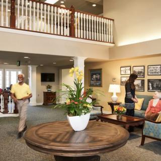 A welcoming lobby area with people interacting, featuring comfortable seating, decorative plants, and artwork on the walls.