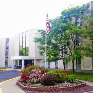 A well-maintained building with a flag in front and vibrant flower beds.