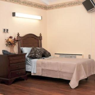 A simple bedroom setup featuring a single bed, wooden dresser, and minimalist decor.