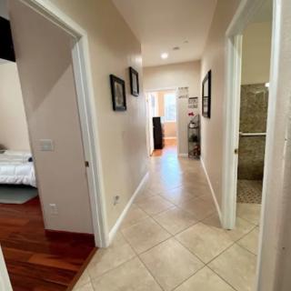 A well-lit hallway with tiled flooring, leading to different rooms in a house.