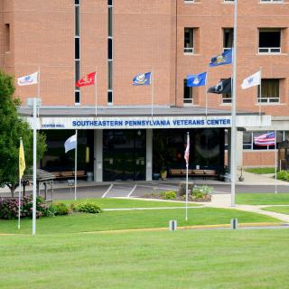 The entrance of a veterans medical center with multiple flags displayed.
