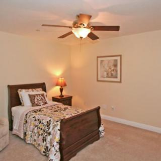 A cozy bedroom with a single bed, warm lighting, and a ceiling fan.