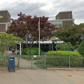 A view of a school building surrounded by greenery and a flagpole.