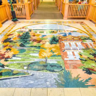 A vibrant floor mural depicting a scenic landscape with trees and a building, enhancing the indoor environment.