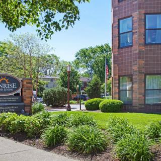 A view of a brick building with well-maintained landscaping and signage in front.