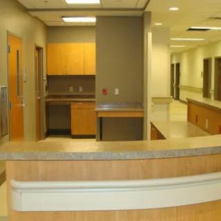 A modern hospital reception area with a desk and hallway.