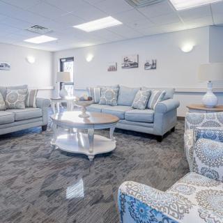 A cozy living room featuring matching sofas and armchairs with patterned upholstery, centered around a round coffee table on a plush carpet.