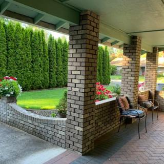 A cozy patio with brick pillars and comfortable seating overlooks a well-maintained garden.