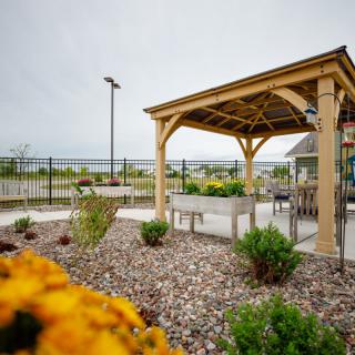 A serene garden with a wooden pergola, benches, and vibrant flowers.