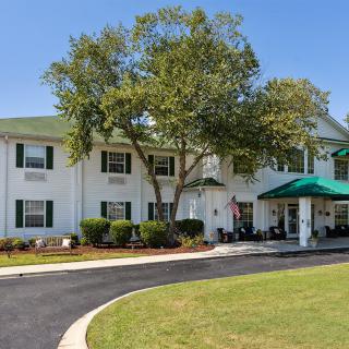 A charming hotel exterior with a green roof and surrounding trees.