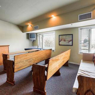 A small chapel with wooden pews and natural light coming through the windows.