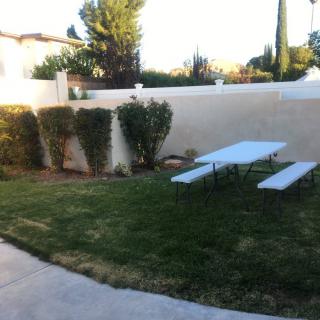 A quiet backyard area with a picnic table and green lawn.