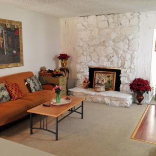 A cozy living room with a stone fireplace, orange couch, and decorative items.