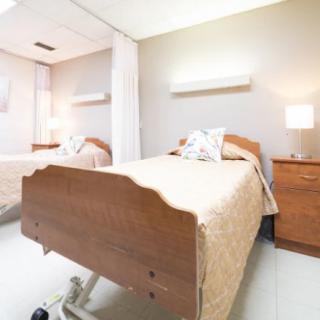 A clean and organized hospital room with two patient beds and warm lighting.