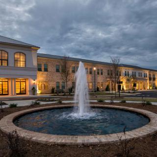 A beautifully lit building with a central fountain illuminated in the evening.