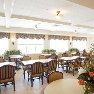 A bright and well-decorated dining room with multiple tables and chairs, featuring large windows that allow plenty of natural light to fill the space.