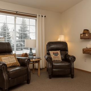 A cozy living room with two reclining chairs and a large window.