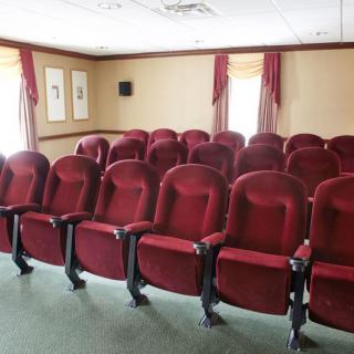 An empty theater with red seats arranged in rows.