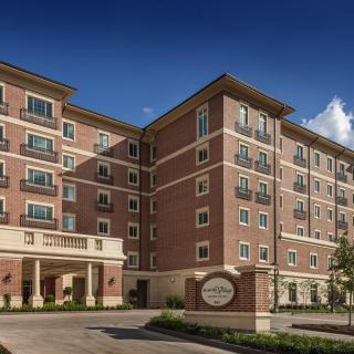 A multi-story hotel building with a brick exterior under a clear blue sky.