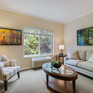 A cozy living room with a modern design, featuring a sofa, armchair, coffee table, and large window.