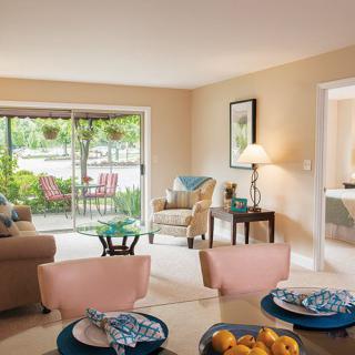 A cozy and modern living room with natural light streaming through a sliding glass door, featuring comfortable furniture and tasteful decor.