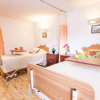 A clean and well-organized hospital room with two beds and medical equipment.