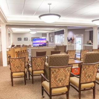 A well-lit living room area with rows of chairs facing a television.