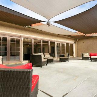 A modern outdoor patio area featuring comfortable wicker furniture and overhead shade sails.