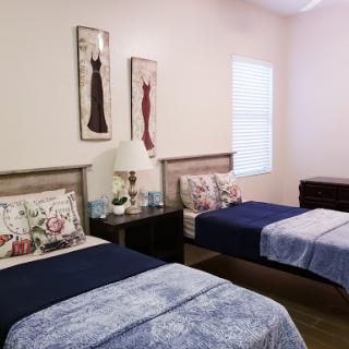 A neatly arranged bedroom featuring two twin beds, decorative pillows, and elegant wall art.