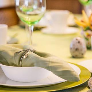 An elegant table setting with a plate, napkin, wine glass, and decorative egg.