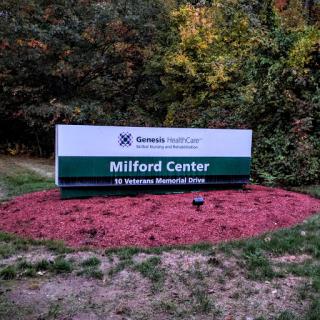 Sign for Milford Center, a healthcare facility surrounded by nature.