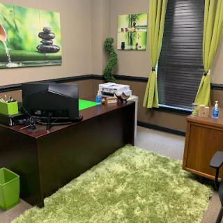 A modern office space featuring green accents, a spacious desk, and calming wall art.