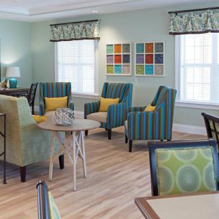 A modern living room with colorful chairs, tables, and wall art.