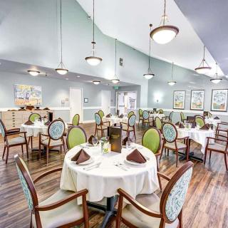 An elegantly set dining room with neatly arranged tables and chairs, showcasing tasteful interior design and ambient lighting.