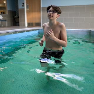 A boy engages in water exercises in a swimming pool.