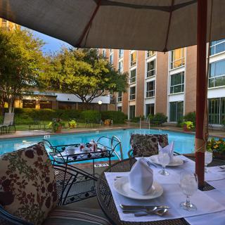 A luxurious outdoor dining area next to a serene swimming pool at a hotel.